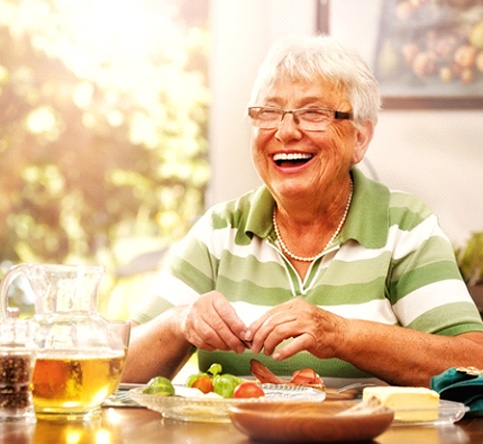 Senior woman smiling with dentures in Westchase at dining table