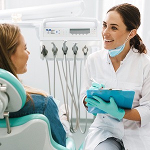Smiling dentist taking notes while talking to patient