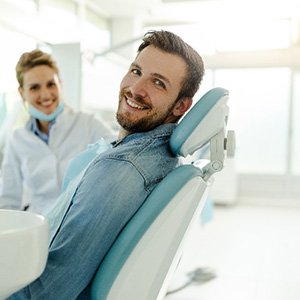 Man in denim shirt smiling while sitting in dental chair