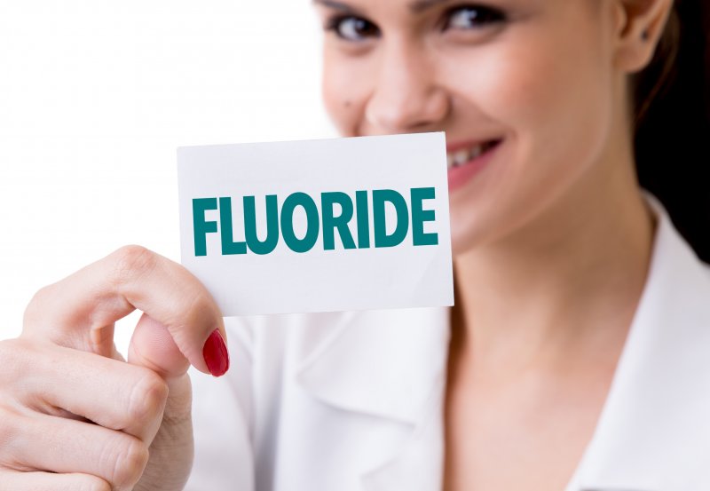 Woman holding paper cared labeled 'fluoride'