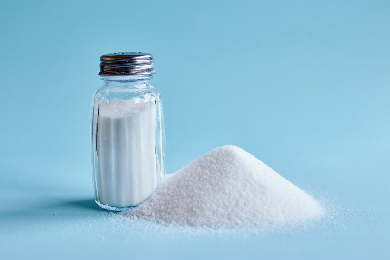 A close-up of a salt shaker against a blue background