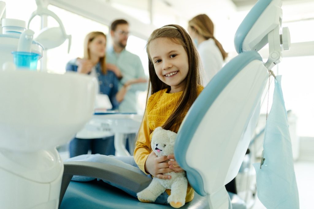 child at dentist’s appointment with parents smiling 