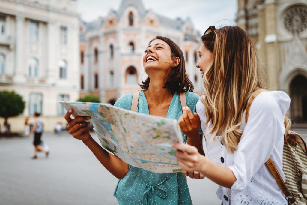 Two girl smiling while looking at map and exploring city