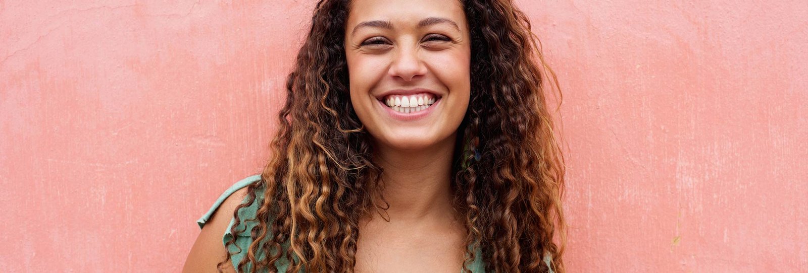 A beautiful young woman in pink background smiling at the camera